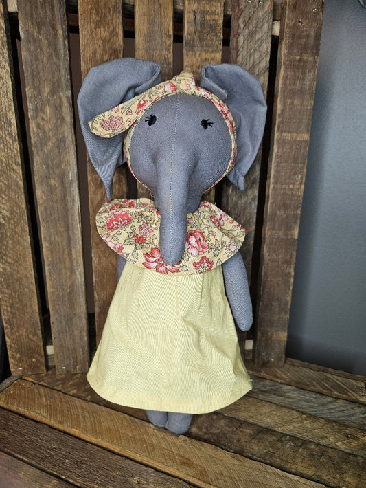 Dark gray elephant with buttercream yellow dress and floral collar