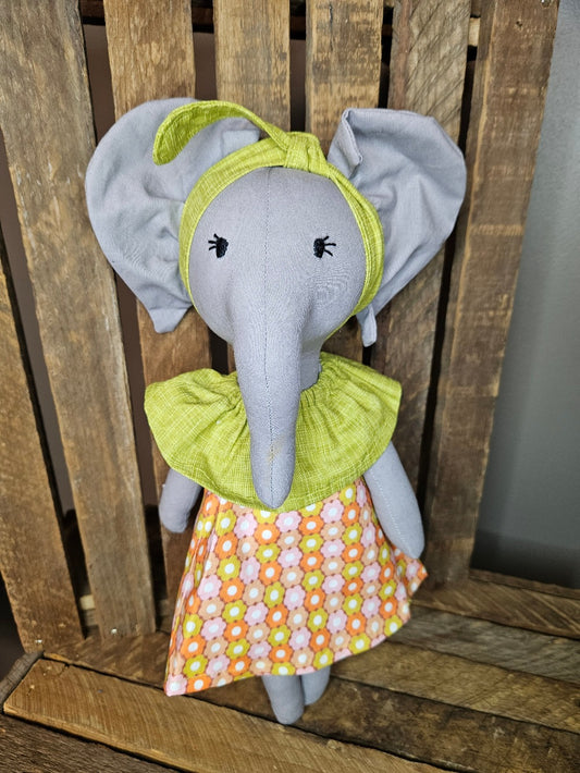 Light gray elephant in a retro green and orange dress