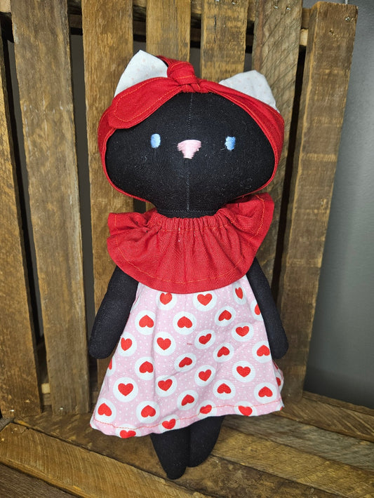 Black kitten with red and pink heart dress